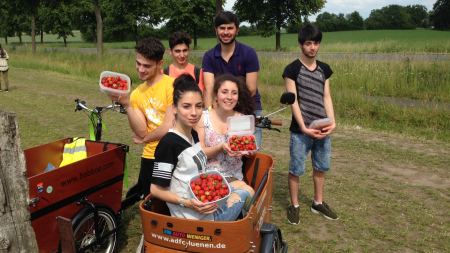 Menschen mit Erdbeeren auf einem Lastenfahrrad