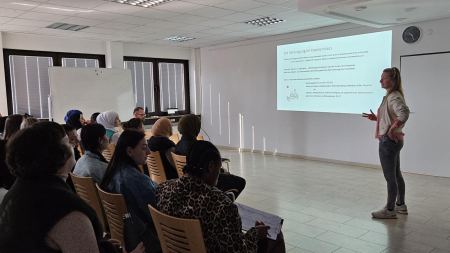 Frau hält Powerpoint-Vortrag vor Publikum