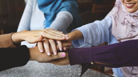 Frauen legen Hände übereinander