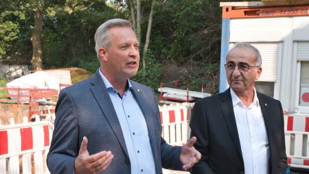 Zwei Männer mit Anzügen vor einer Baustelle