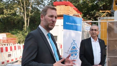 Zwei Männer mit Anzügen vor einer Baustelle