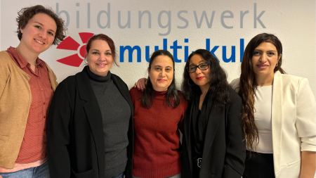 Fünf Frauen stehen vor dem Schriftzug "Bildungswerk Multi Kulti" und lächeln in die Kamera.