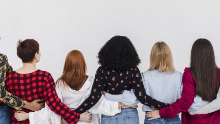 Rückenansicht diverser Frauen, die mit verschränkten Armen Schulter an Schulter stehen
