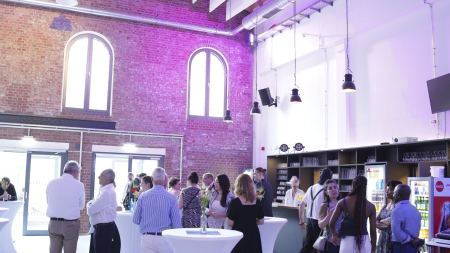 Menschen stehen in einem festlich beleuchteten Gebäude. Im Hintergrund ist eine Bar.