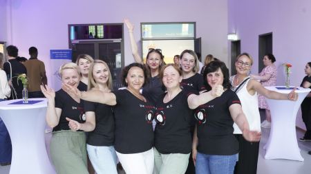 Eine Frauengruppe mit schwarzen T-Shirts posiert vor der Kamera.