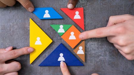 Finger verschiedener Hände zeigen auf bunte Puzzleteile 