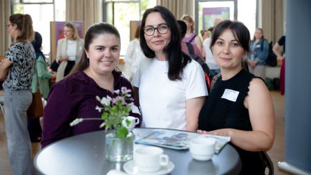Drei Frauen lächeln in die Kamera.