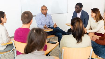 Menschen sitzen in einem Stuhlkreis und diskutieren