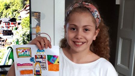Die Gewinnerin des Wettbewerbs mit ihrem Bild und dem Preis Mädchen hält selbstgemaltes Bild und Präsentpaket in der Hand