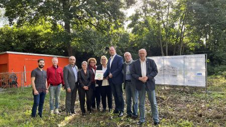 Gruppenfoto mit sechs Männern und drei Frauen auf einem Baugrundstück