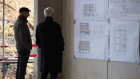 Gäste schauen auf den Bauplan an der Wand