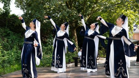 Auf einer Bühne tanzen Frauen in traditionellen Gewändern. 