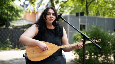 Eine Frau mit Saz singt in ein Mikrofon. 