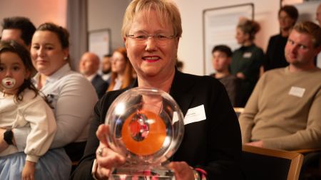 Preisträgerin hält Pokal in der Hand