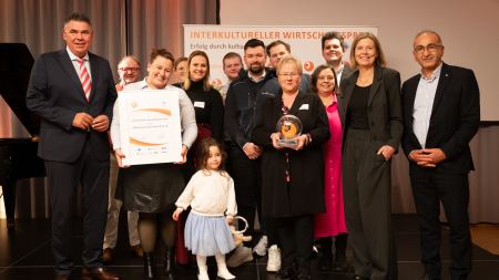 Preisträgerteam mit Pokal und Urkunde auf der Bühne