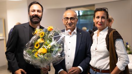 Drei Personen mit Blumenstrauß stehen nebeneinander.