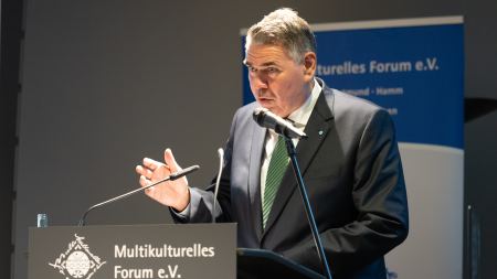 Landrat Mario Löhr steht an einem Mikrofon und hebt die Hand.