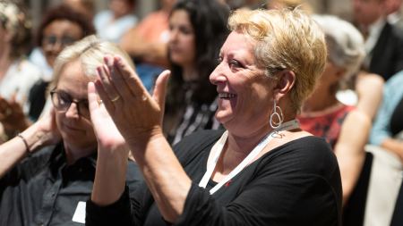 Eine Frau sitzt im Publikum und klatscht.