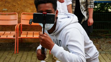 Jugendlicher hält Smartphone mit Selfiestick