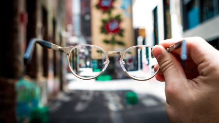 Brille schwebt vor Straßenansicht mit hohen Häusern