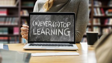aufgeklappter Laptop auf einem Tisch. Auf dem Display steht: "Never stop learning"