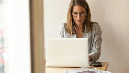 Frau sitzt mit Kopfhörern vorm Laptop