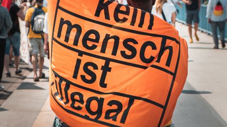 Kein Mensch ist illegal Zwei Menschen tragen Banner mit Aufschrift "Kein Mensch ist illegal"