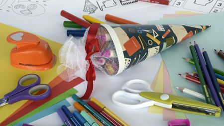 bunte Schultüte liegt zwischen verschiedenen Bastelmaterialien