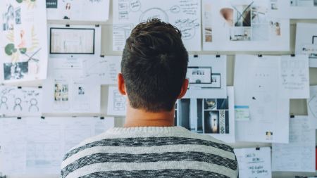Person steht vor Whiteboard mit Arbeitsblättern