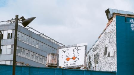 Plakatwand zwischen Betongebäuden mit Aufschrift "Stay human"