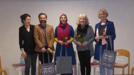 Vier Frauen und ein Mann stehen mit "Stark durch Vielfalt"-Taschen auf dem Podium
