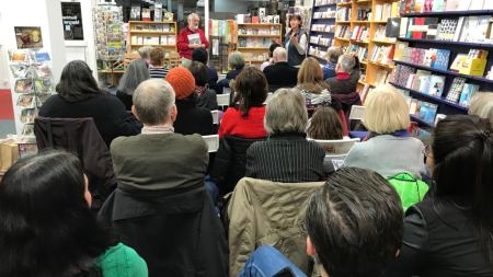 Menschen sitzen in Stuhlreihen in einer Buchhandlung