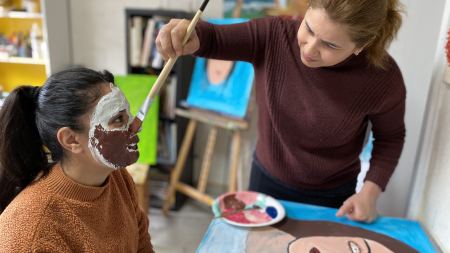 Kunstworkshop Frauenwoche Hamm Frau bemalt Gipsmaske auf dem Gesicht einer anderen Frau