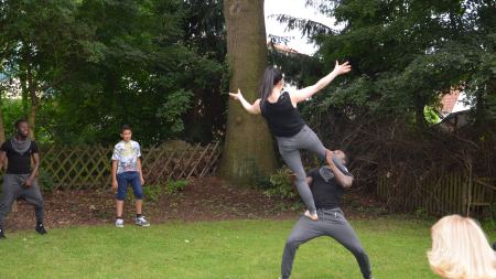 akrobatische Hebefigur mit stehendem Mann und auf ihm balancierender Frau im Garten