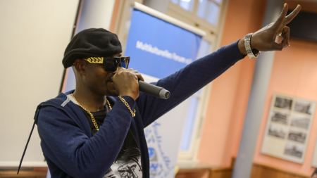 Rapper am Mikro, Peace Mann mit Mikro in rechter Hand macht Peace-Zeichen mit linker Hand