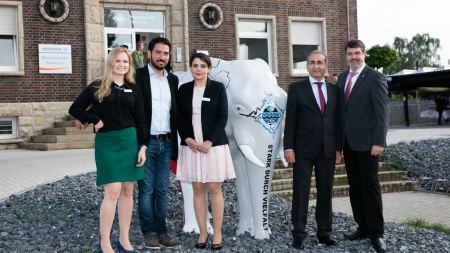 Personengruppe vor Hammer Geschäftsstelle Michael Thews, Kenan Küçük, Canan Çabuk, Taylan Kutlar, Monika Koppe mit Elefantenfigur vor Hammer Geschäftsstelle
