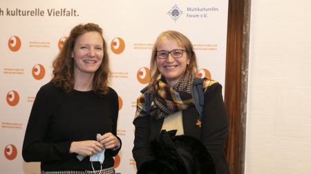 Zwei Frauen lächeln vor Fotowand "Interkultureller Wirtschaftspreis"