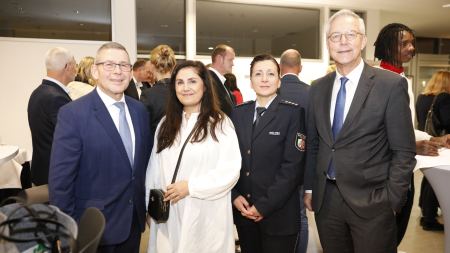 Zwei Männer in Anzug, eine Frau in weißem Kleid und eine Frau in Polizeiuniform posieren fürs Foto