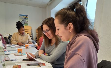 Bewerbungstraining im Projekt MY TURN. MY CAREER. Vier Frauen sitzen an einem Tisch. Sie halten Zettel in der Hand und lesen.
