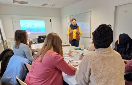 Bewerbungstraining im Projekt MY TURN. MY CAREER. Vier Frauen sitzen mit dem Rücken zur Kamera an einem Tisch. Sie schauen zu einer Frau vor ihnen, die sie anschaut.