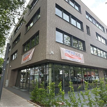 Gebäude mit Fensterfront und Hecke