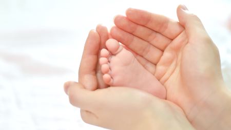 ein Babyfuß in der Hand eines Erwachsenen 