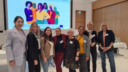 Acht Frauen posieren in Tagungsraum lächelnd für ein Gruppenbild