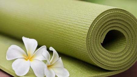 Aufgerollte, grüne Yogamatte mit weißer Blüte