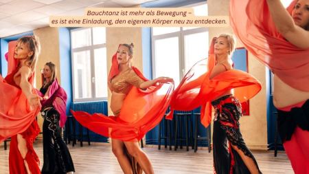 Fünf Frauen schwingen orangefarbene Tücher durch die Luft. Sie tragen Röcke mit Verzierungen.