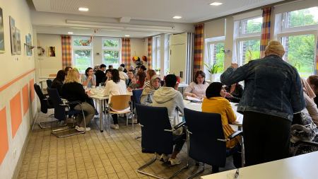 Frauen sitzen um mehrere Tische herum und sind im Gespräch