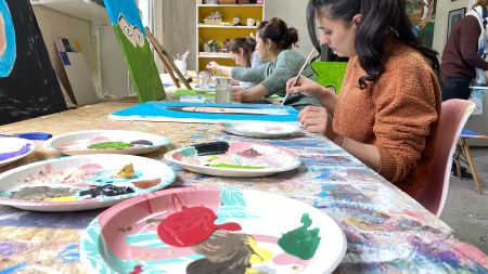 Pappteller mit Acrylfarben und malende Frauen in Atelier