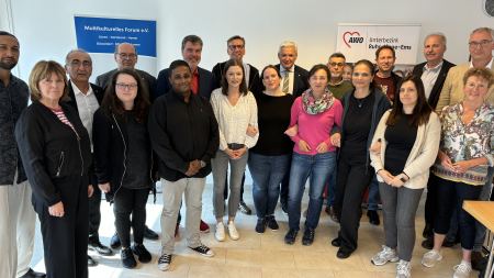 Gruppe von Menschen hat sich im Halbkreis aufgestellt und blickt in die Kamera