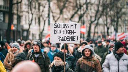 Menschen auf einer Demonstration, Frau hält Schild mit der Aufschrift "Schluss mit der Lügen-Pandemie"