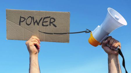 Eine Hand hält ein Megaphon, die andere ein Schild mit der Aufschrift "Power", von dem ein Pfeil Richtung Megaphon ausgeht